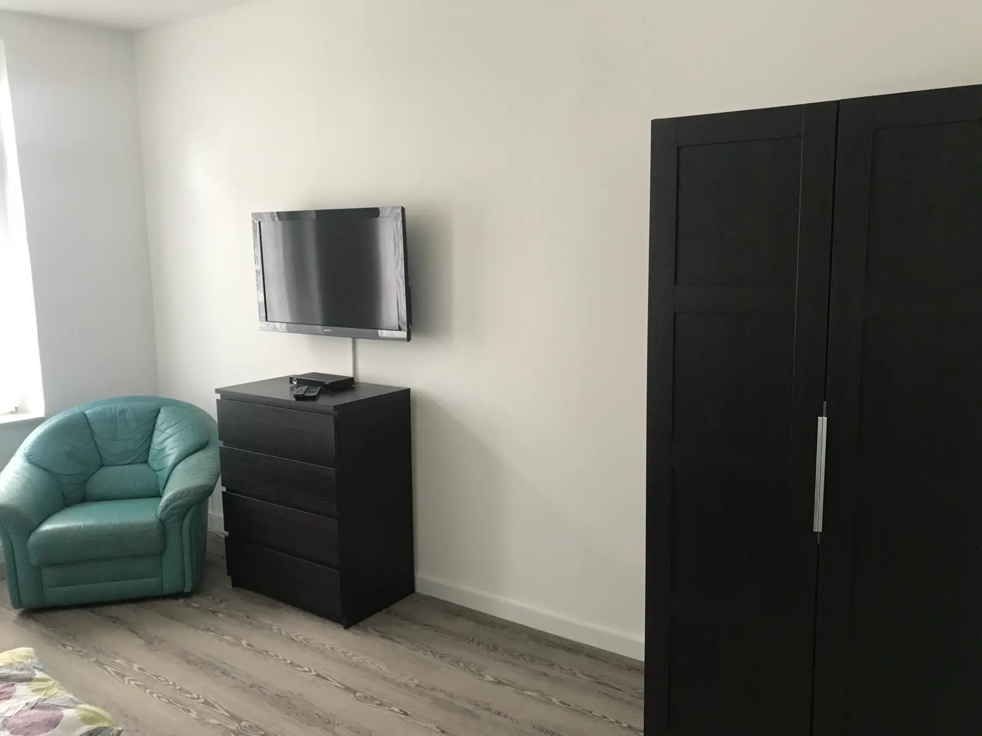 Schlafzimmer mit Sessel, TV und Kleiderschrank