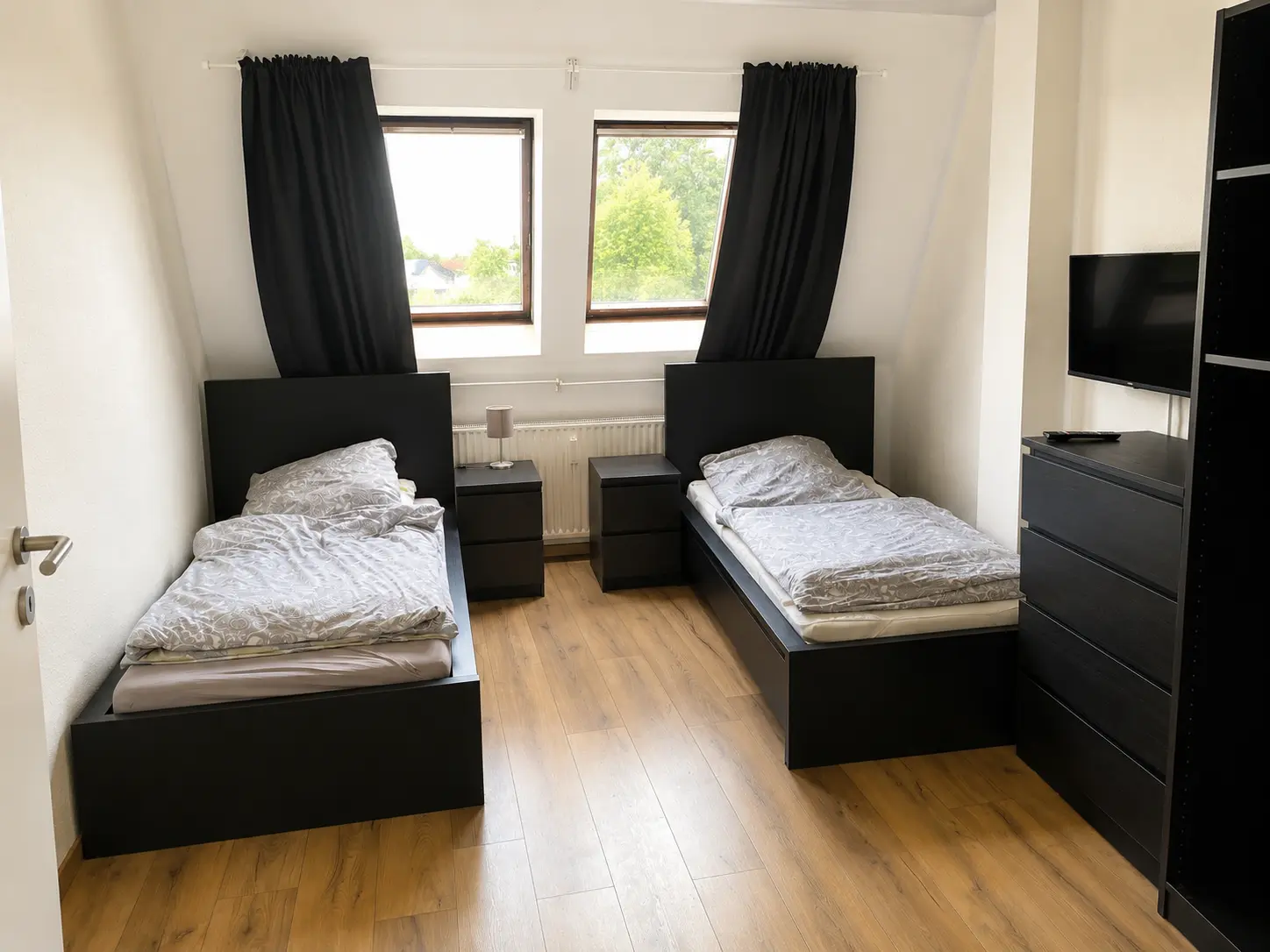 Helles Schlafzimmer mit zwei Einzelbetten und TV