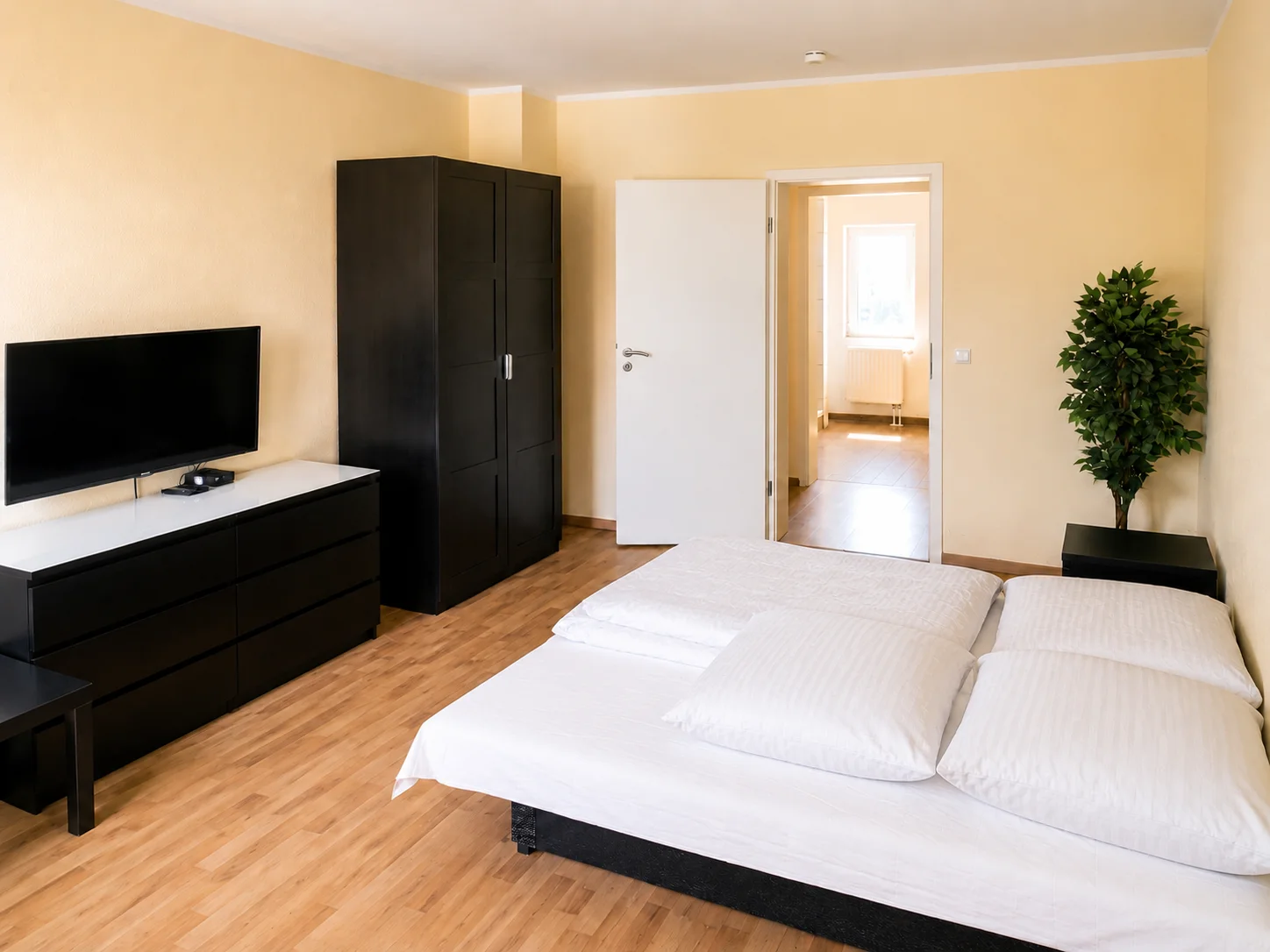 Schlafzimmer mit Doppelbett, Einzelbett und Zimmerpflanze