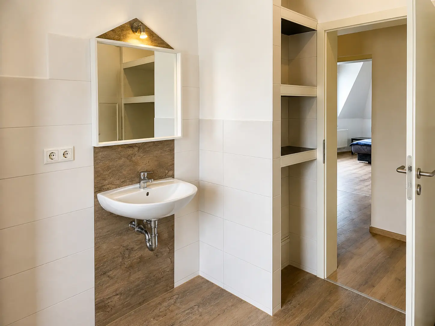 Badezimmer mit Waschbecken, Spiegel und Ablagen