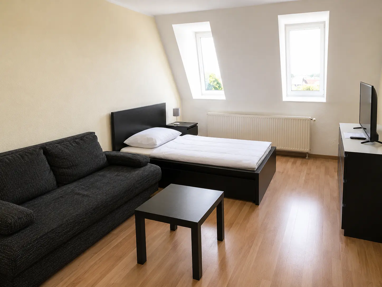 Heller Wohn- und Schlafbereich mit Sofa und Dachfenstern