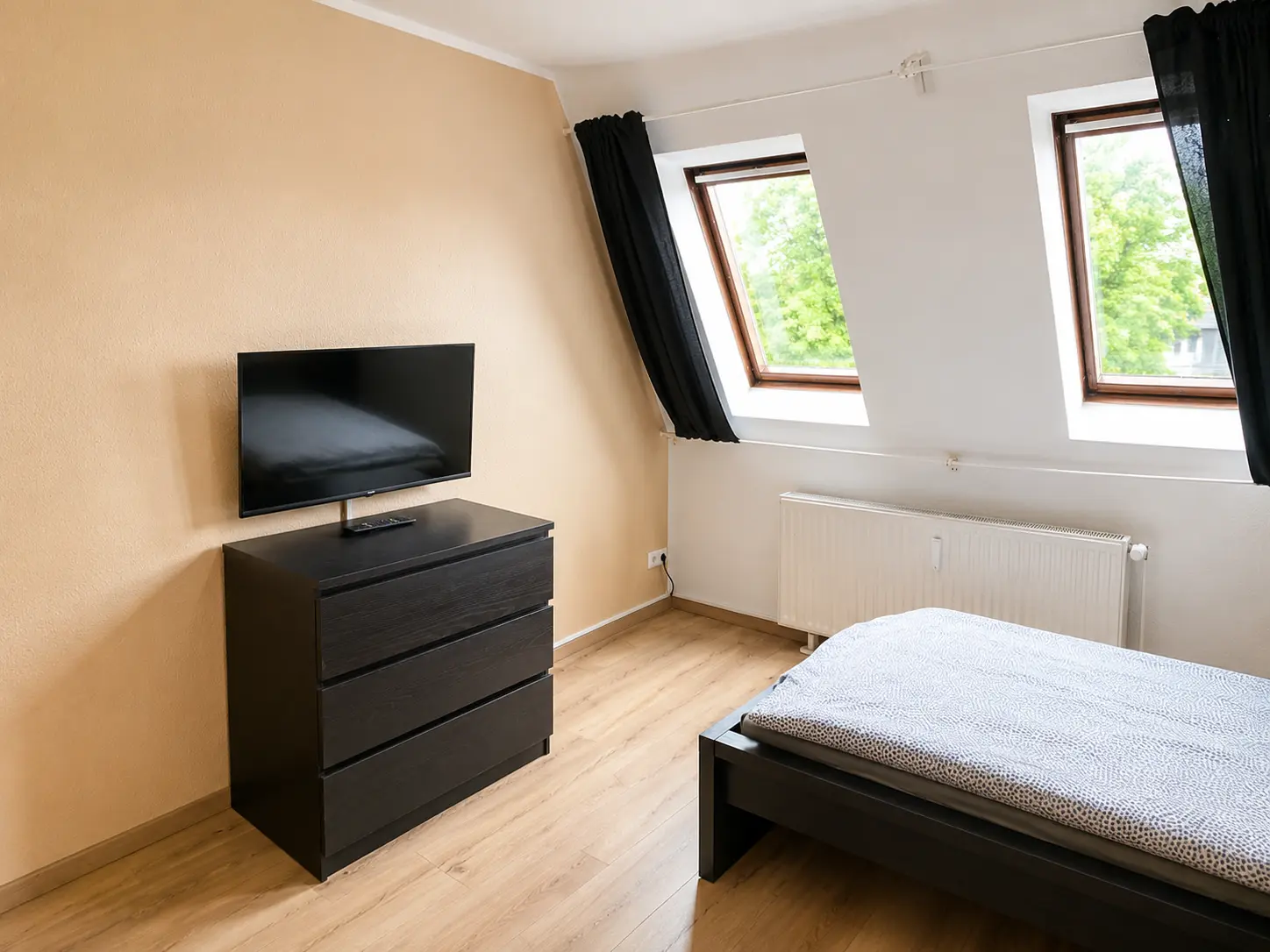 Schlafzimmer mit Bett, Kommode und TV