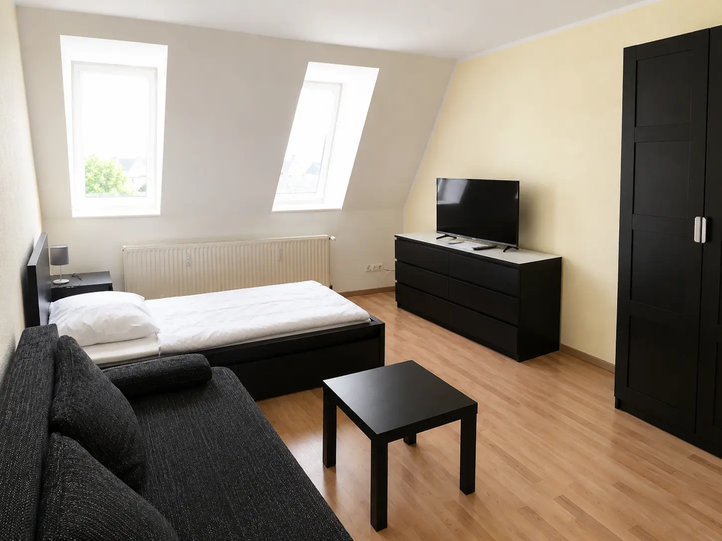 Wohnbereich mit Schlafcouch, Bett und Kleiderschrank