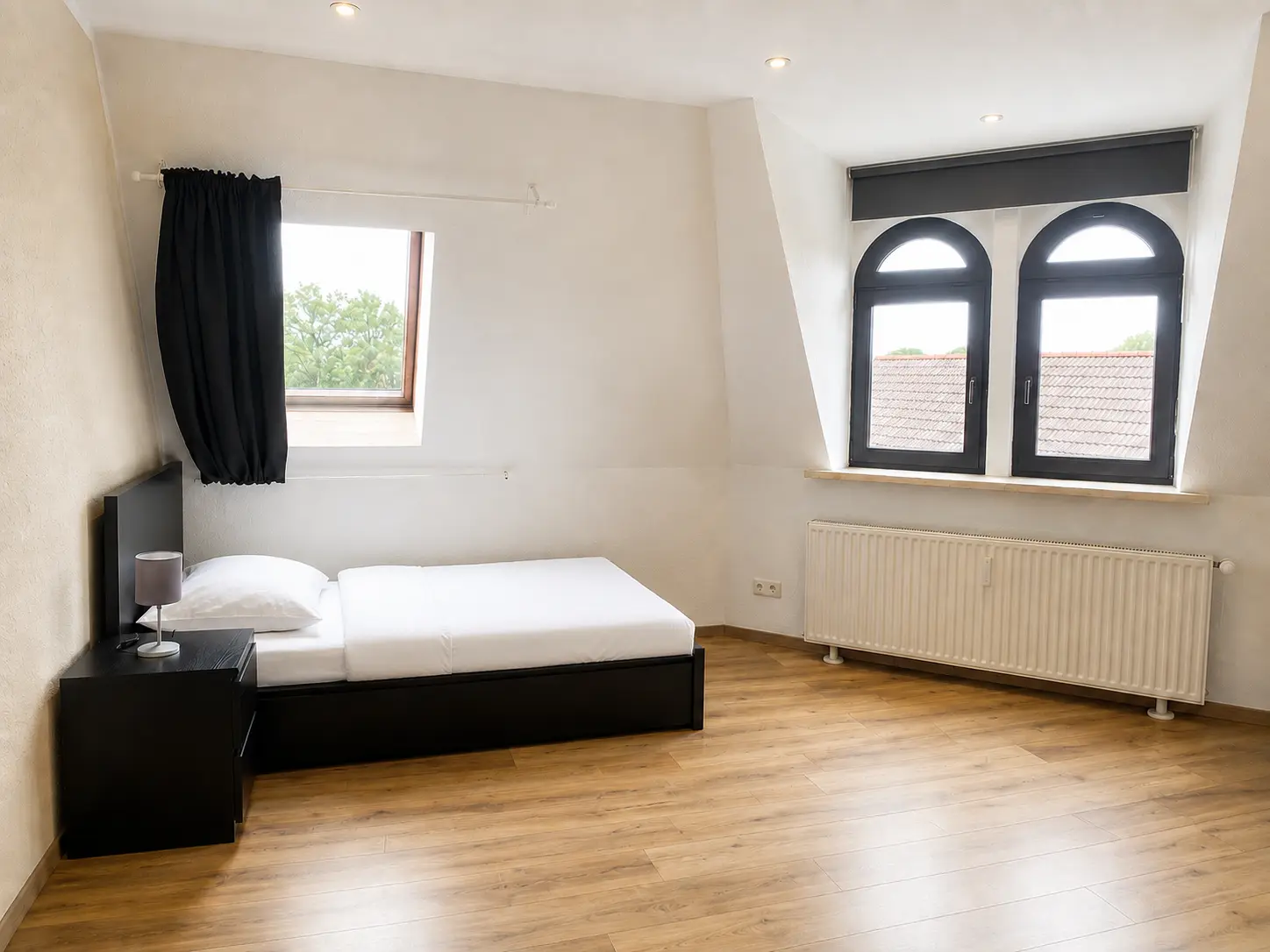 Schlafzimmer mit Doppelbett und Rundbogenfenstern